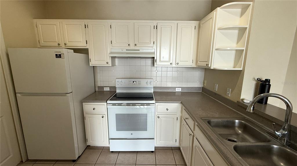 A kitchen with white cabinets, a white refrigerator, a white stove, and a double sink — 2615 MAITLAND CROSSING WAY UNIT 204, ORLANDO, FL
