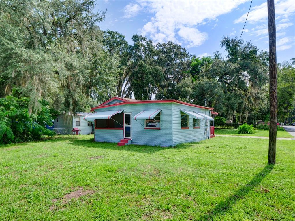 An empty room features white walls, wood-look flooring, and three windows — 813 NW 5TH STREET, WEBSTER, FL