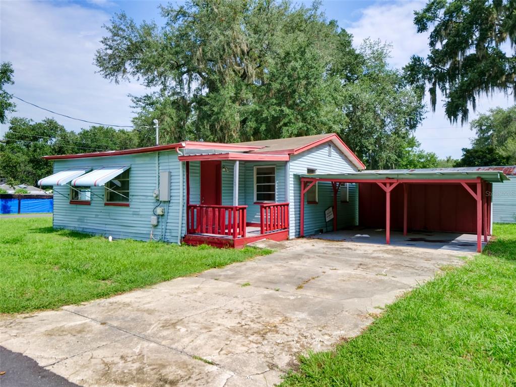 An empty room with white walls, wood-look flooring, and a doorway leading to a kitchen — 813 NW 5TH STREET, WEBSTER, FL