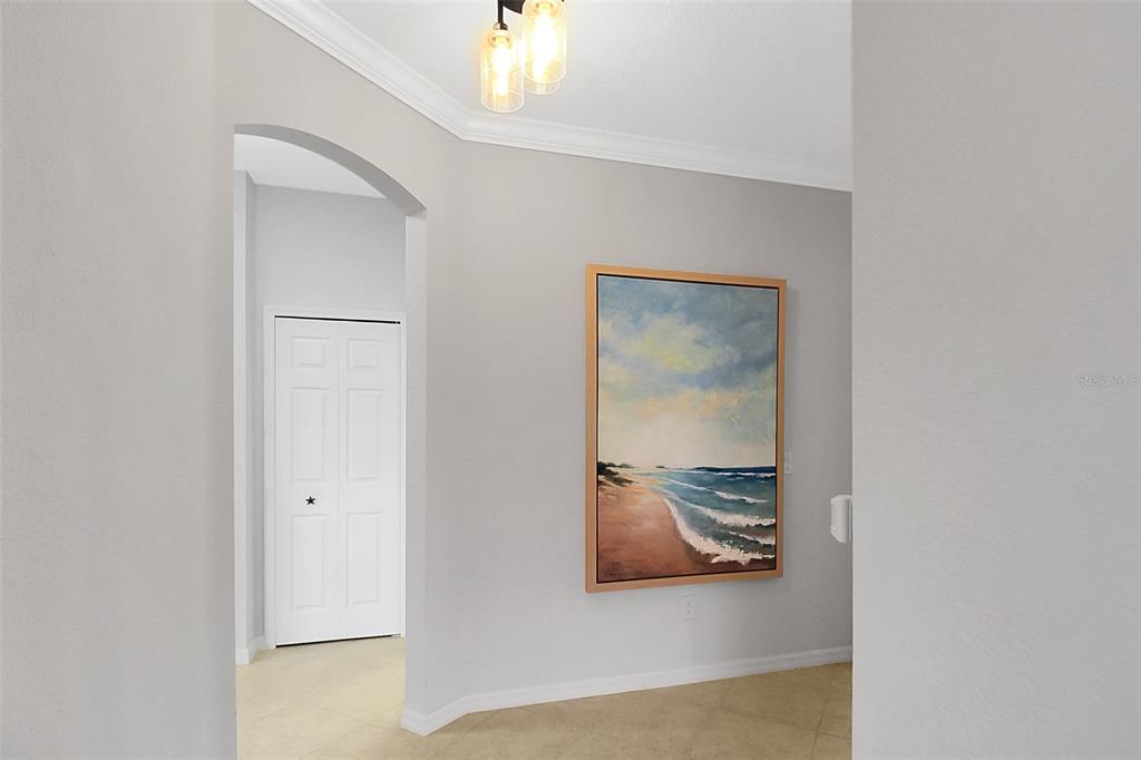 A hallway features light gray walls, tile flooring, a beach-themed painting, and a white door — 20230 TESORO DRIVE, VENICE, FL