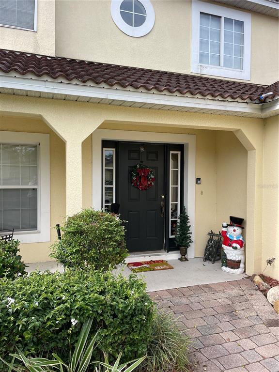 The exterior of a house features a dark front door, a snowman decoration, and landscaping — 153 HUMMINGBIRD PASS, DAVENPORT, FL