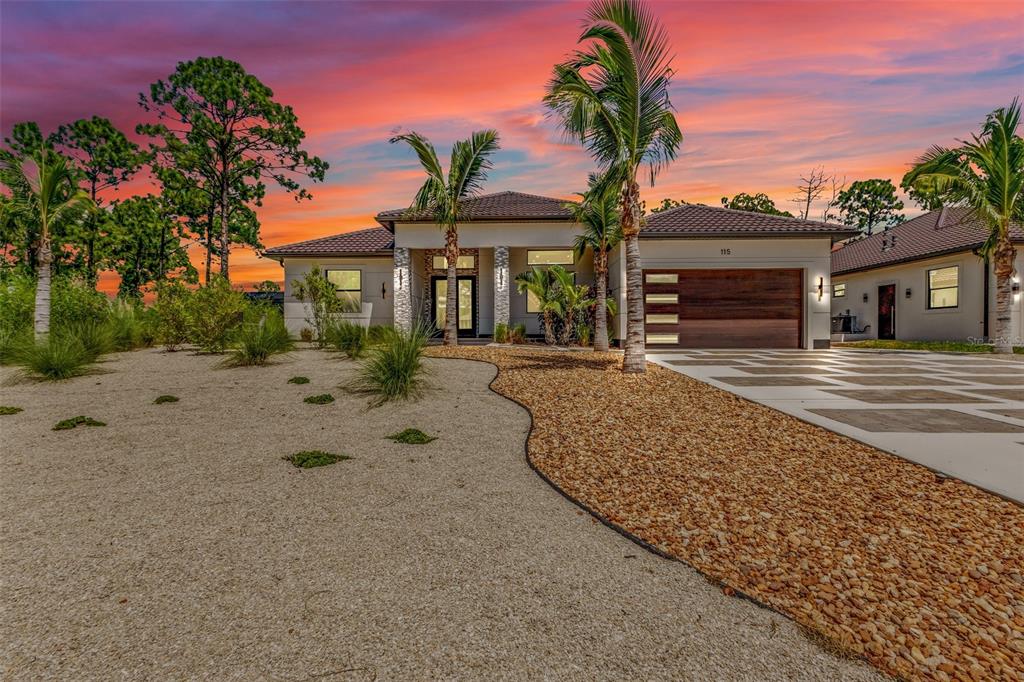 A modern single-story house with a gravel front yard and a paved driveway at sunset — 115 SOLANA STREET, NORTH PORT, FL