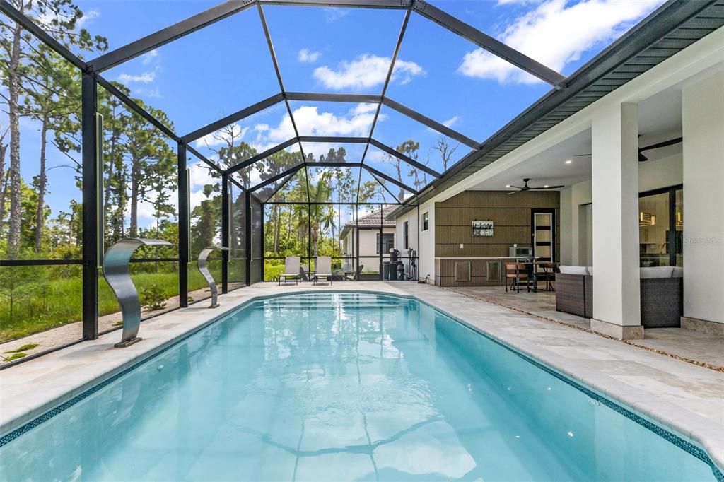 A screened-in swimming pool with water features sits on a patio next to a house — 115 SOLANA STREET, NORTH PORT, FL