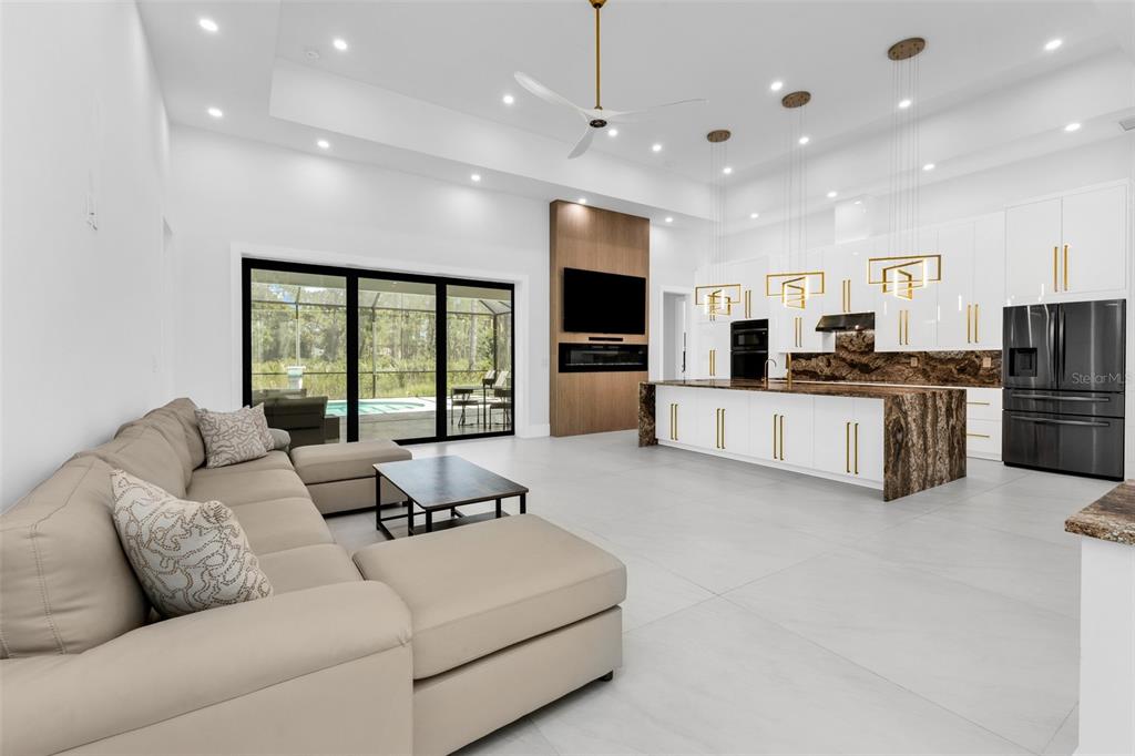 A modern open-concept living room and kitchen featuring white cabinetry, stone countertops, and sliding doors — 115 SOLANA STREET, NORTH PORT, FL