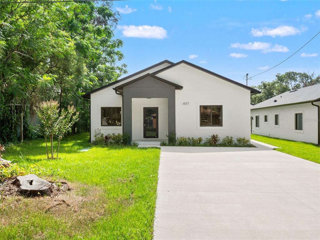 A modern, white single-story house with a grey entryway and a concrete driveway — 497 OCEAN AVENUE, APOPKA, FL