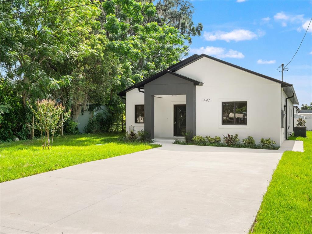 A white single-story house with a dark gray entryway and a concrete driveway — 497 OCEAN AVENUE, APOPKA, FL