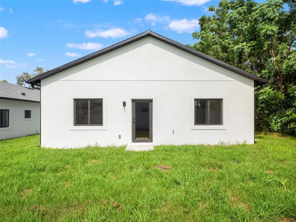 The exterior of a white, single-story house features a central door flanked by two windows — 497 OCEAN AVENUE, APOPKA, FL
