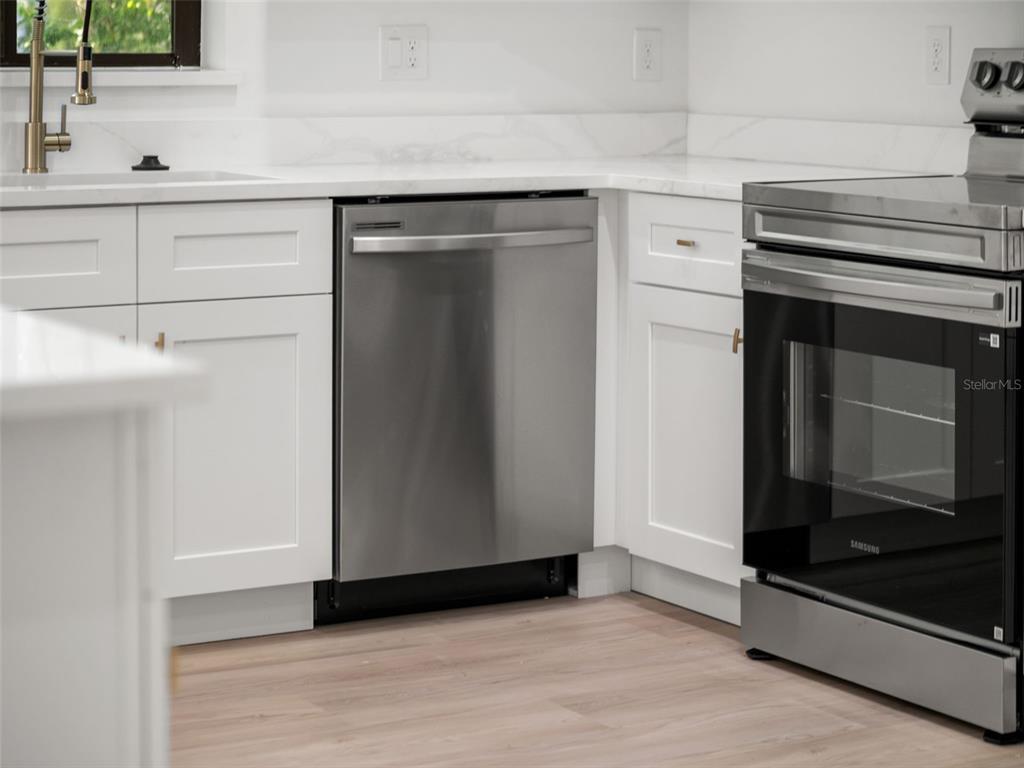 A kitchen features white cabinets, stainless steel appliances, and a light-colored countertop — 497 OCEAN AVENUE, APOPKA, FL
