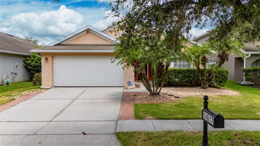 A single-story suburban house with a two-car garage, a paved driveway, and a landscaped front yard — 14617 KEELFORD WAY, ORLANDO, FL