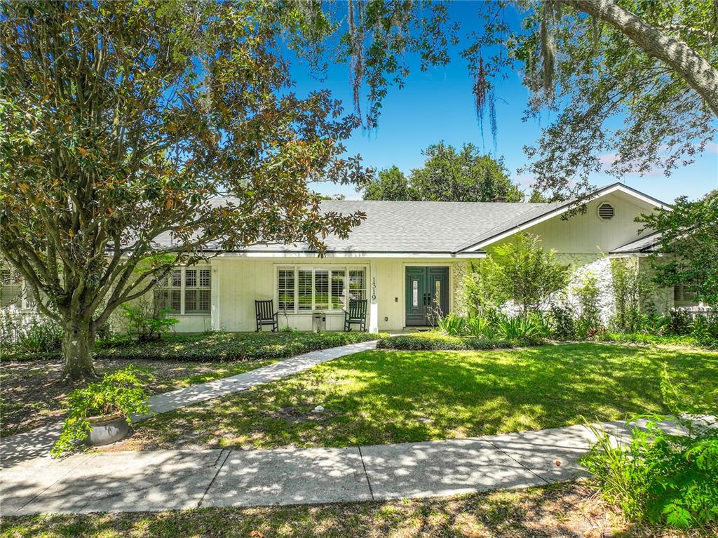 A single-story house with a white exterior, gray roof, and a front walkway under large trees — 1319 BUCKWOOD DRIVE, ORLANDO, FL