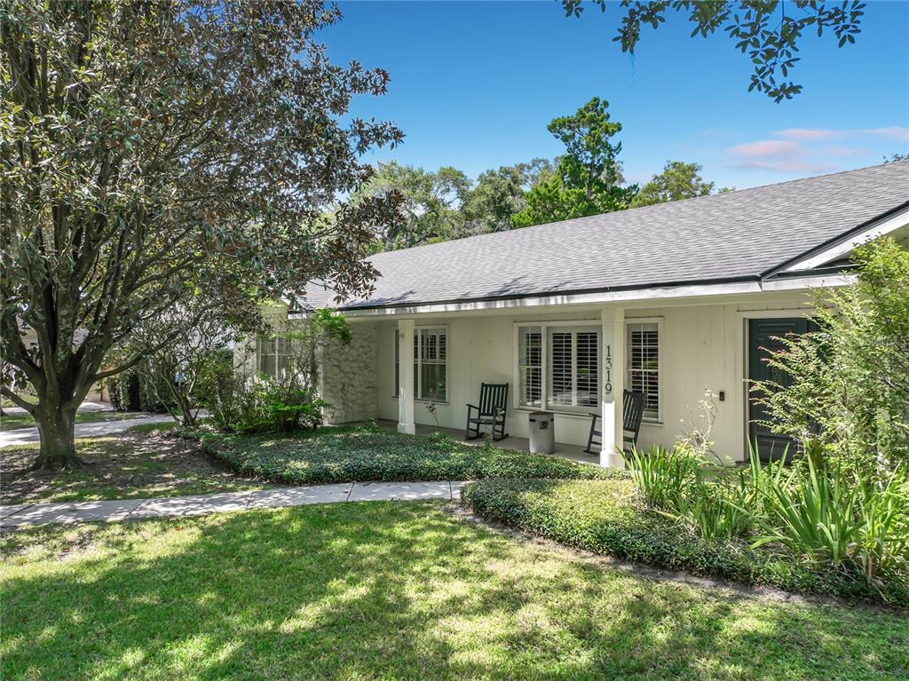 A single-story house with a white exterior, a front porch, and a large tree — 1319 BUCKWOOD DRIVE, ORLANDO, FL