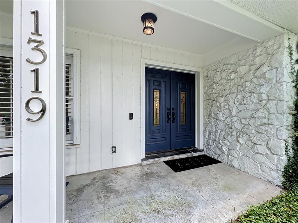A front porch features a blue double door, white vertical siding, and a stone wall — 1319 BUCKWOOD DRIVE, ORLANDO, FL