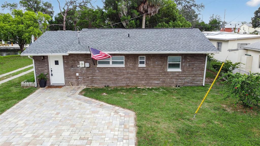 A single-story house with brown horizontal siding, a gray shingled roof, and a paved driveway — 5411 TEAL DRIVE, WEEKI WACHEE, FL