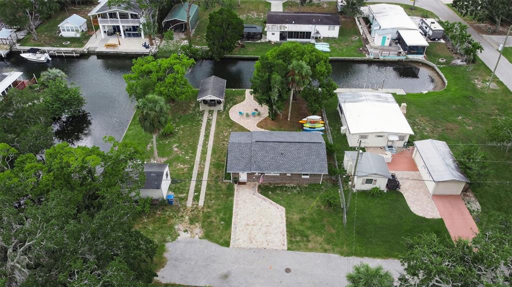 An aerial view shows a house with a paved driveway, backyard patio, and canal access — 5411 TEAL DRIVE, WEEKI WACHEE, FL