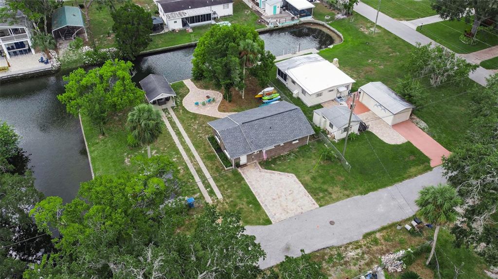 An aerial view shows a house with a gray roof, a canal, and a paved driveway — 5411 TEAL DRIVE, WEEKI WACHEE, FL