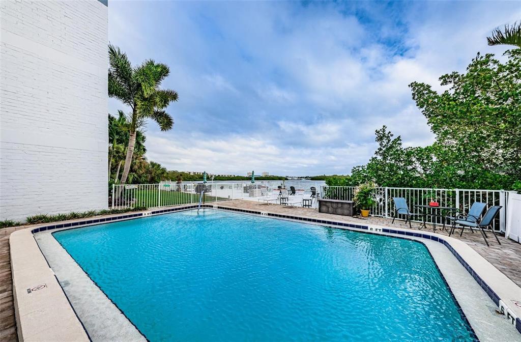 A white deck with two chairs overlooks a large body of water under a cloudy sky — 1859 SHORE DRIVE S UNIT 107, SOUTH PASADENA, FL