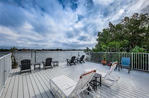 A spacious wooden deck overlooks a body of water with various outdoor seating options — 1859 SHORE DRIVE S UNIT 107, SOUTH PASADENA, FL