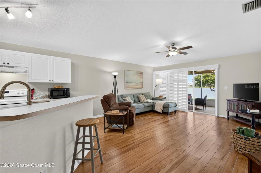 An open-concept living room and kitchen feature wood-look flooring and a sliding glass door — 2336 DEERCROFT DRIVE, MELBOURNE, FL