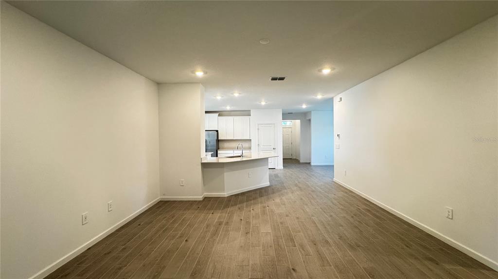 An open-concept living area features light wood-look tile flooring and a kitchen with white cabinets — 19447 SW 79TH STREET, DUNNELLON, FL