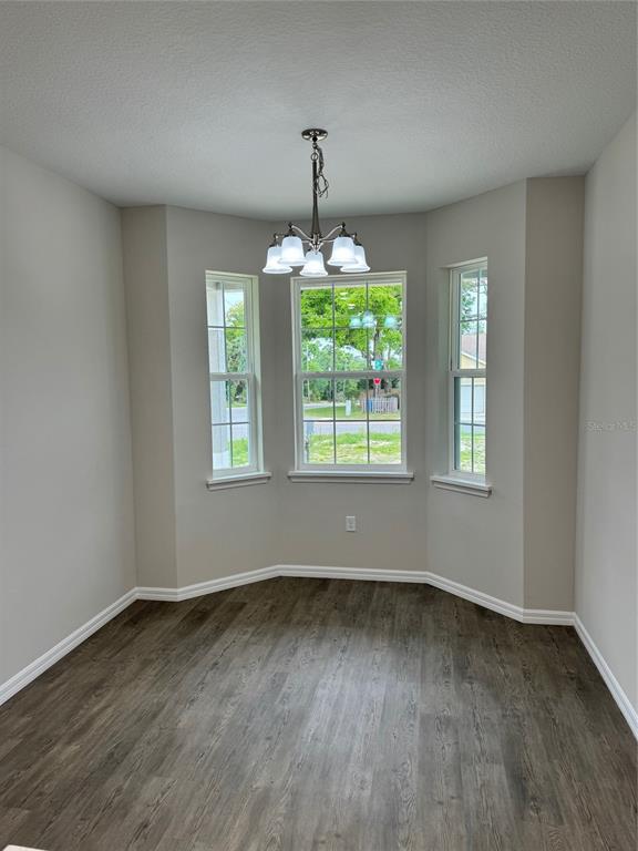 A dining area with wood-look flooring, a bay window, and a hanging light fixture — 1013 FOOTE STREET, EUSTIS, FL