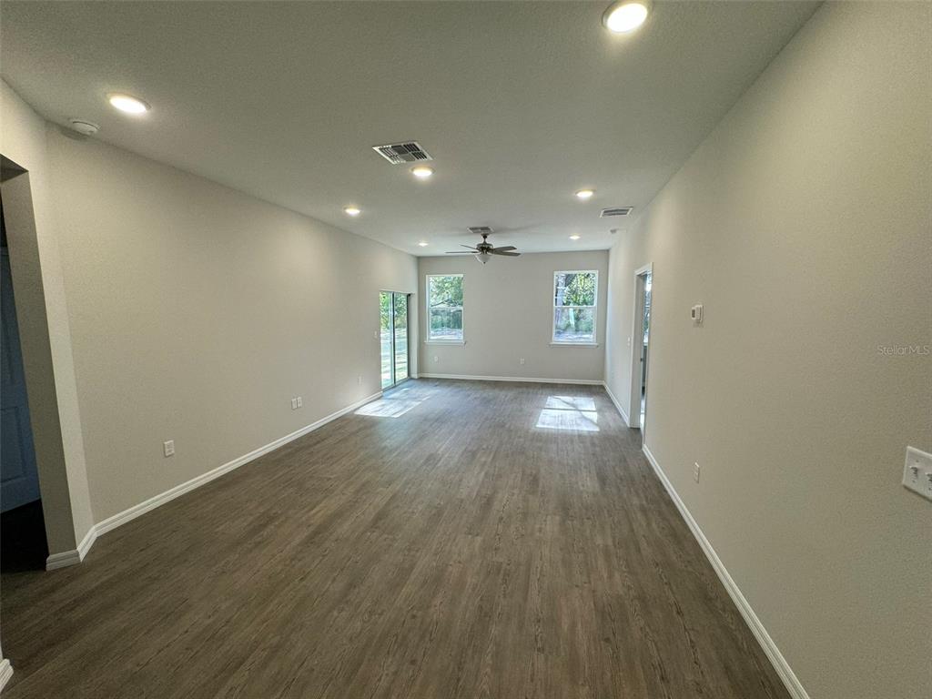 An empty living room features light-colored walls, recessed lighting, and wood-look flooring — 1013 FOOTE STREET, EUSTIS, FL