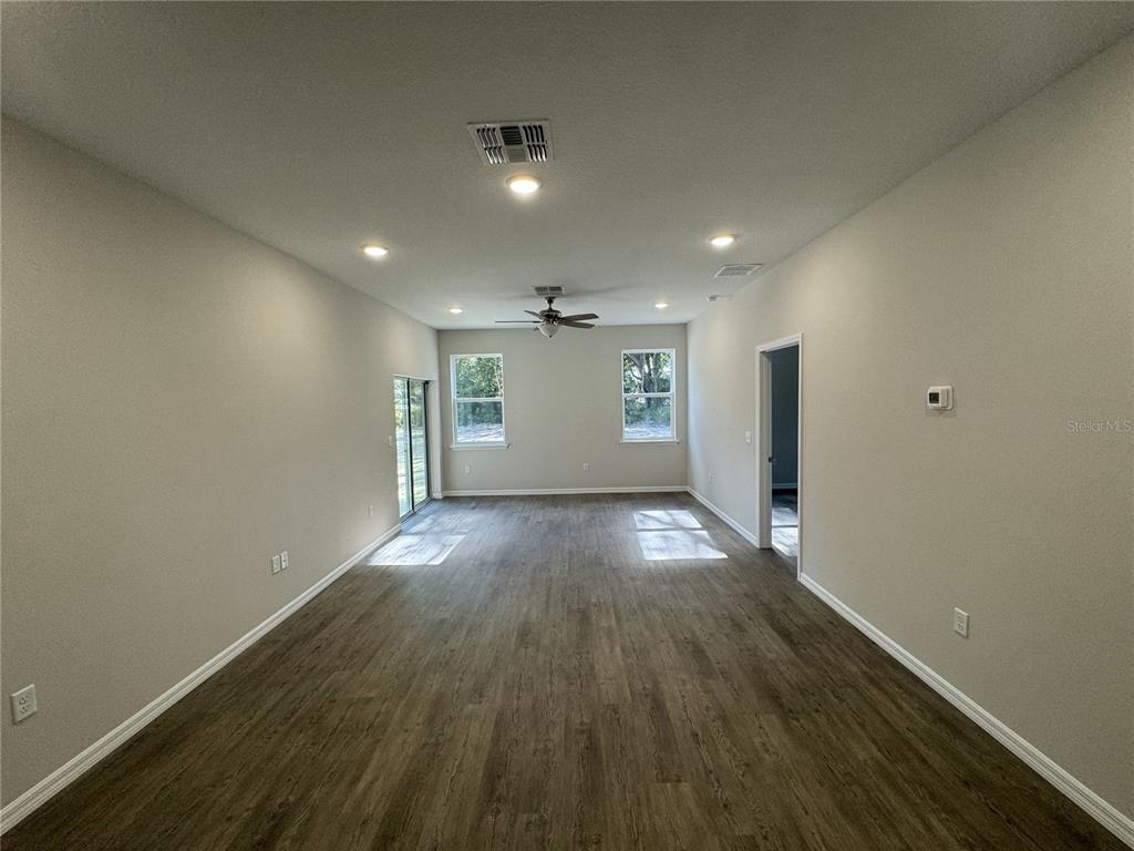 An empty living room features light-colored walls, recessed lighting, a ceiling fan, and wood-look flooring — 1013 FOOTE STREET, EUSTIS, FL
