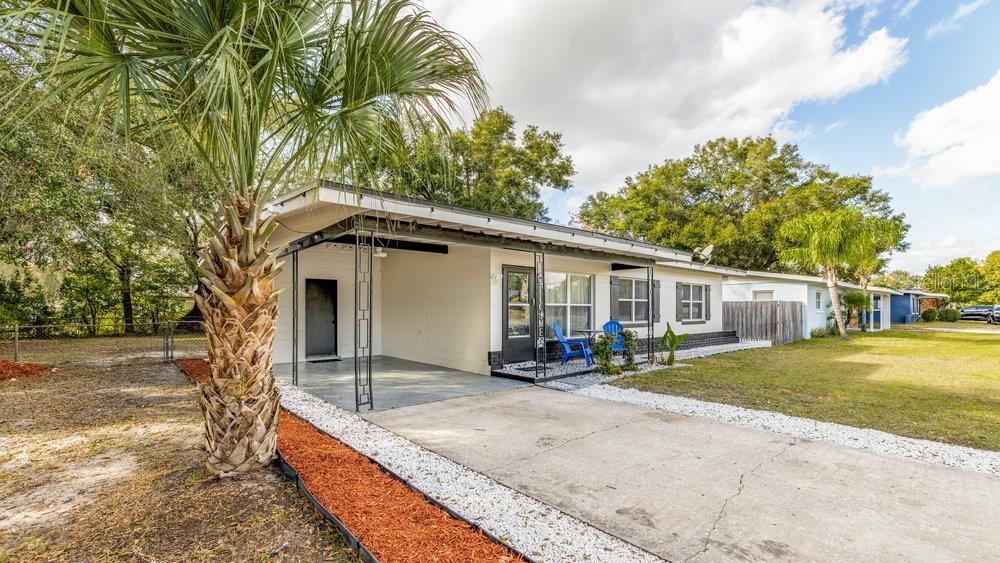 A single-story house with a carport, white exterior, and a concrete driveway with gravel borders — 1406 CONWAY ROAD, ORLANDO, FL