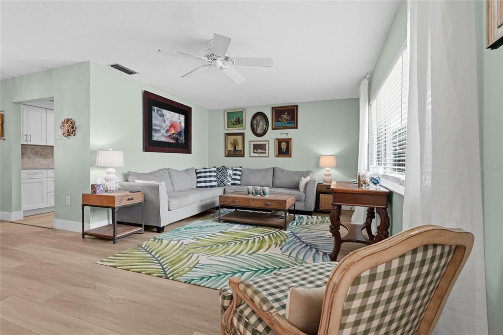 A living room features a gray sectional sofa, a palm-patterned rug, and light green walls — 3274 SAVAGE ROAD, SARASOTA, FL