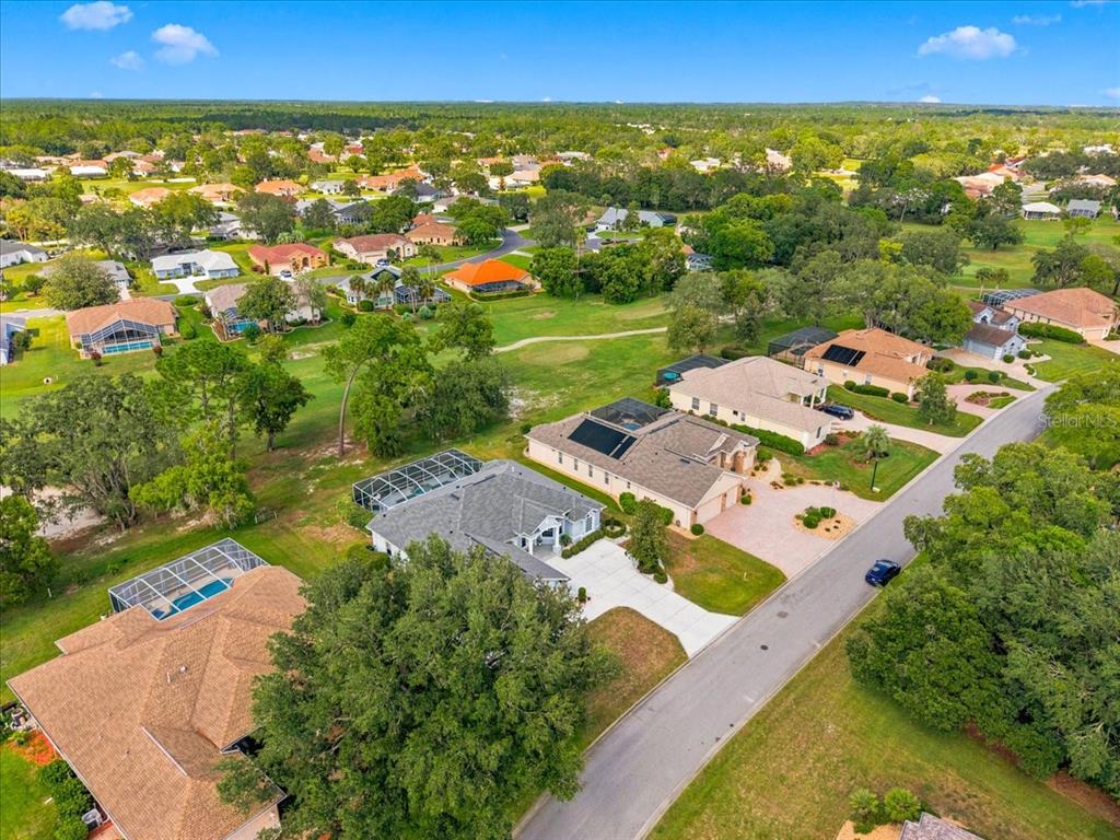 An aerial view shows several suburban houses with swimming pools and solar panels near a golf course — 9251 GRAND CYPRESS DRIVE, WEEKI WACHEE, FL