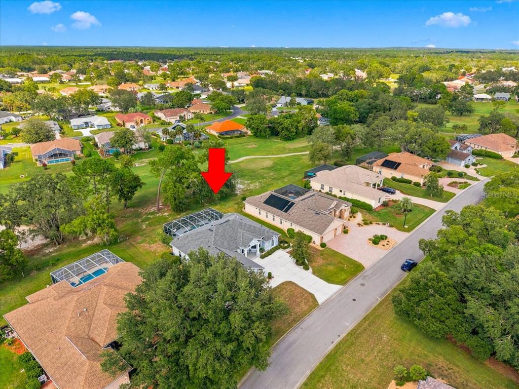 An aerial view shows a residential neighborhood with houses, swimming pools, and a golf course — 9251 GRAND CYPRESS DRIVE, WEEKI WACHEE, FL
