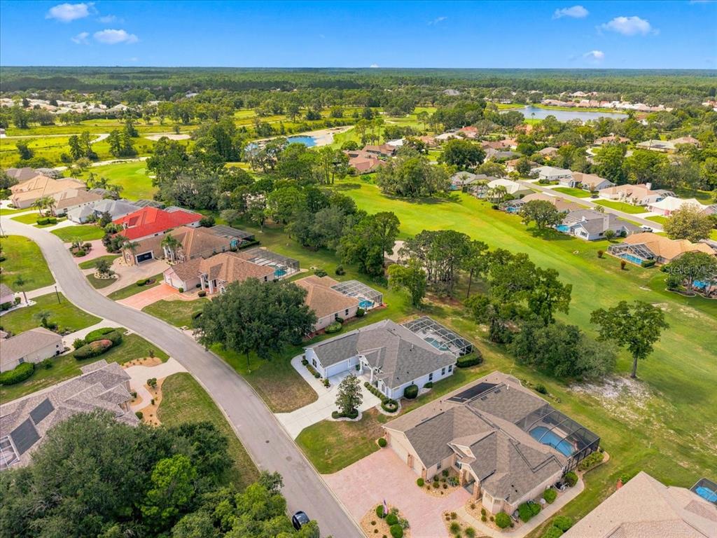 An aerial view shows several suburban houses with swimming pools bordering a green golf course — 9251 GRAND CYPRESS DRIVE, WEEKI WACHEE, FL