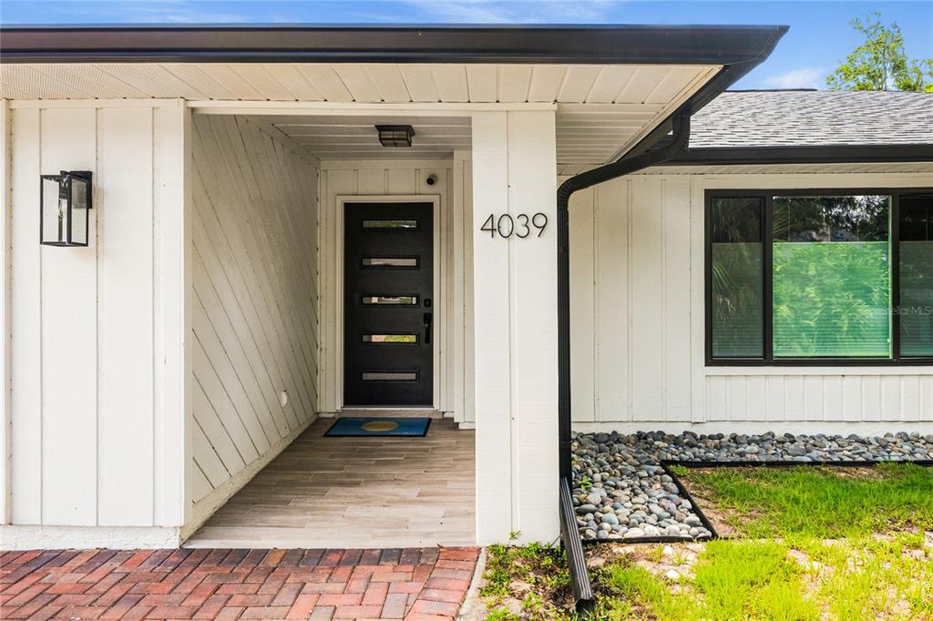 The exterior of a house features a white facade, a black front door, and brick pavers — 4039 COOL WATER COURT, WINTER PARK, FL