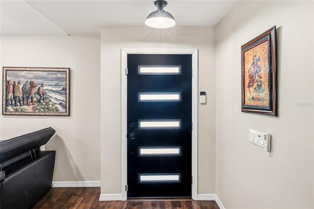 A black front door with five horizontal glass panels sits between two framed wall paintings — 4039 COOL WATER COURT, WINTER PARK, FL