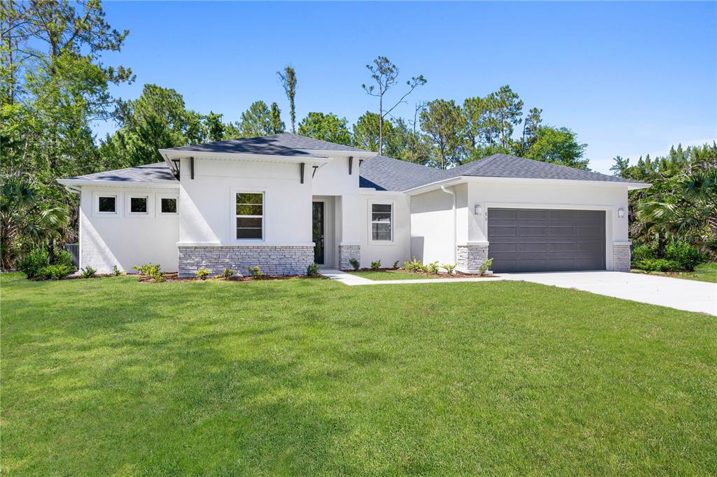 A white single-story house with a gray roof, stone accents, and a two-car garage — 13 SW 34TH PLACE, CAPE CORAL, FL