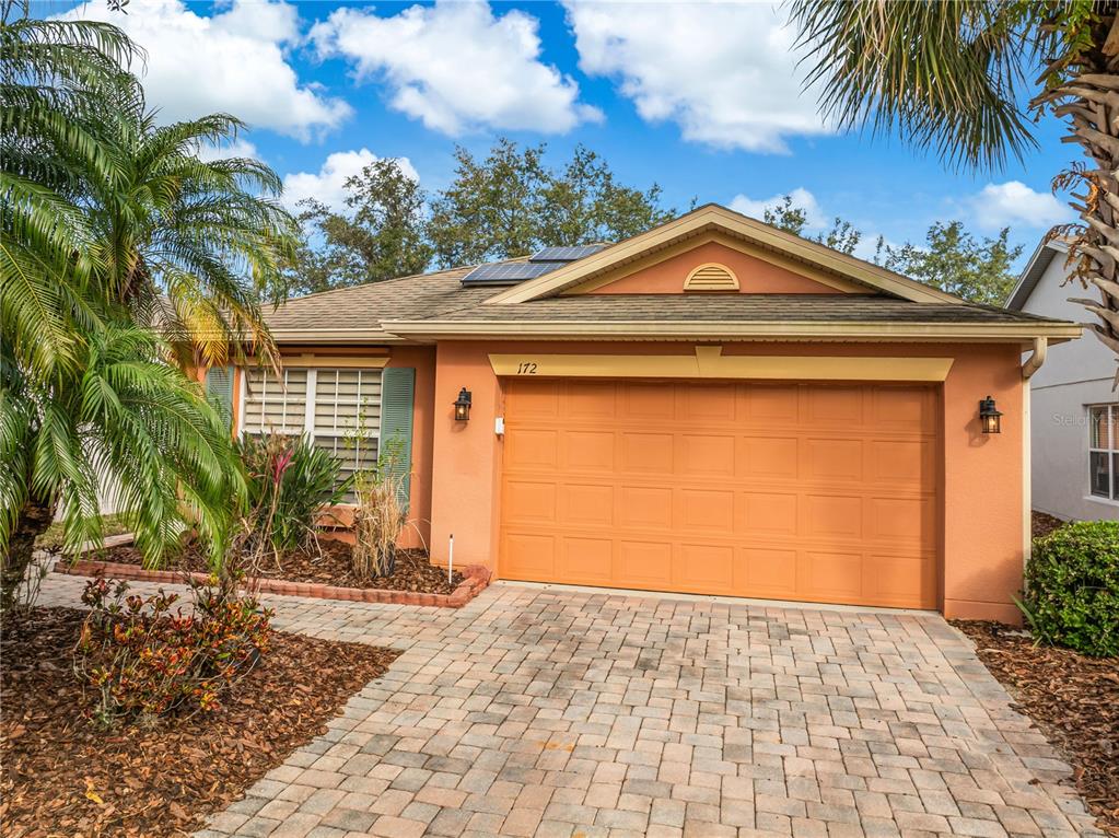 A single-story house with a tan stucco exterior, a two-car garage, and a paved driveway — 172 ACADIA DRIVE, KISSIMMEE, FL