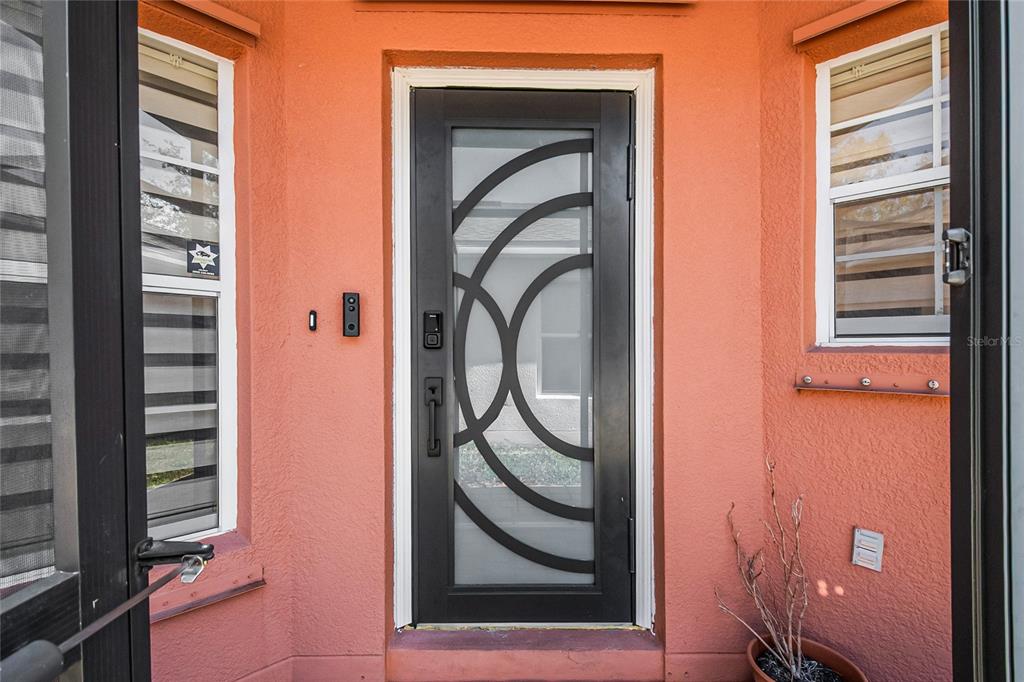 A dark gray front door with a circular glass design sits between two windows — 172 ACADIA DRIVE, KISSIMMEE, FL