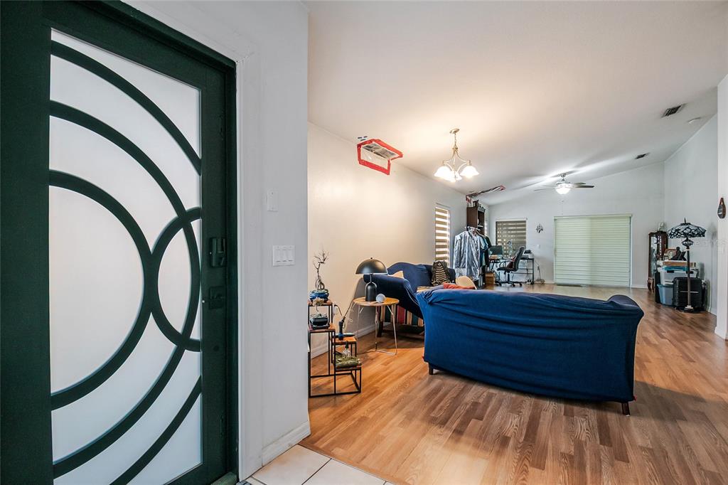 An entryway opens into a living room with wood-look flooring and a blue sofa — 172 ACADIA DRIVE, KISSIMMEE, FL