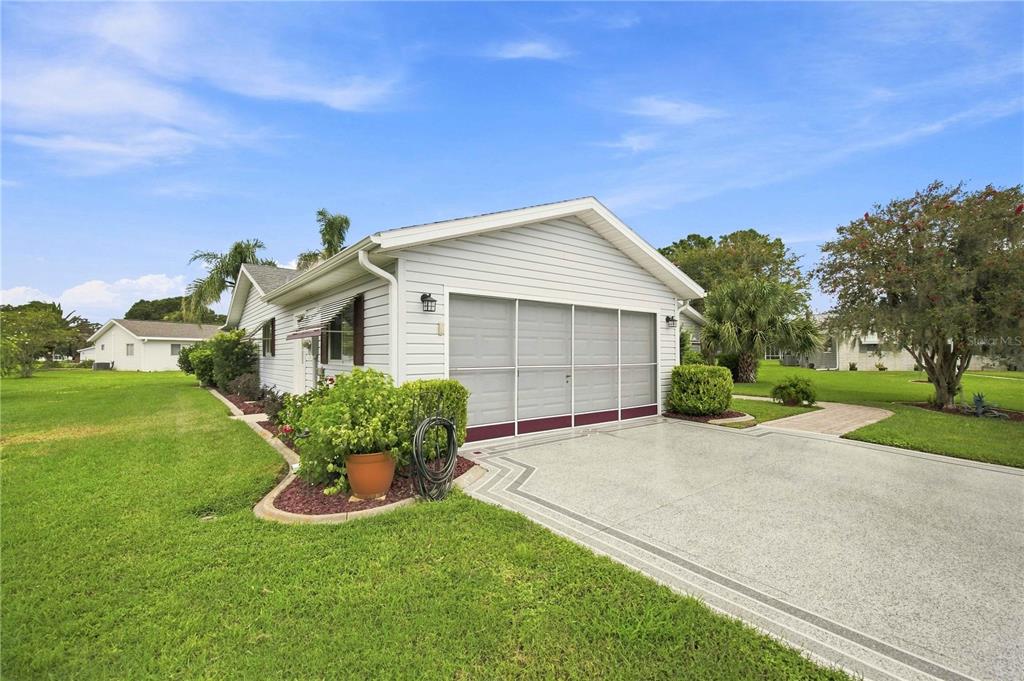 A white house with a garage and a paved driveway sits on a grassy lawn — 17790 SE 101ST COURT, SUMMERFIELD, FL
