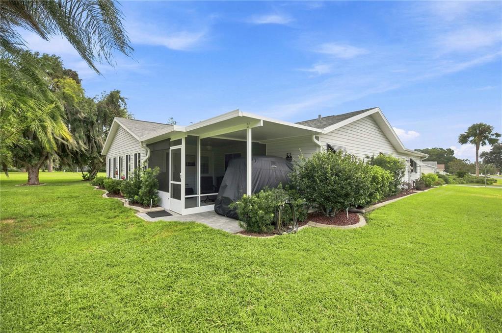 A side view of a house with a screened-in patio and a large grassy yard — 17790 SE 101ST COURT, SUMMERFIELD, FL