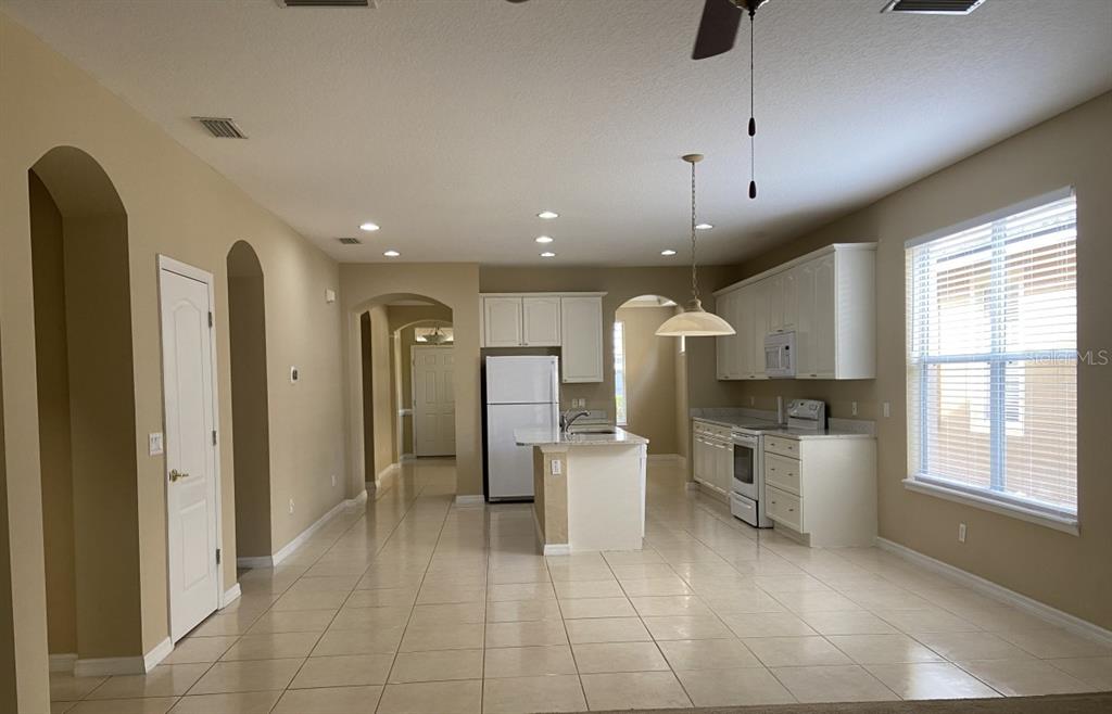 A kitchen with white cabinets, a center island, and tile flooring in an open-concept space — 6679 DUNCASTER STREET, WINDERMERE, FL