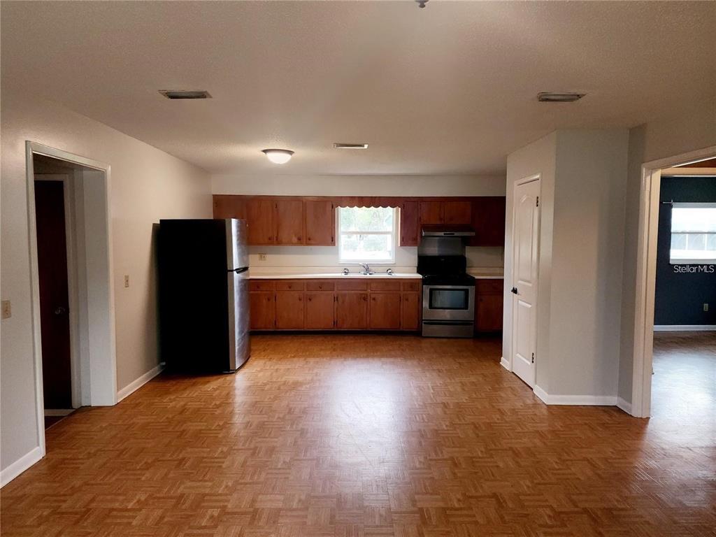 A kitchen features wood cabinets, stainless steel appliances, and parquet flooring in an open space — 420 N COURT STREET, BRONSON, FL