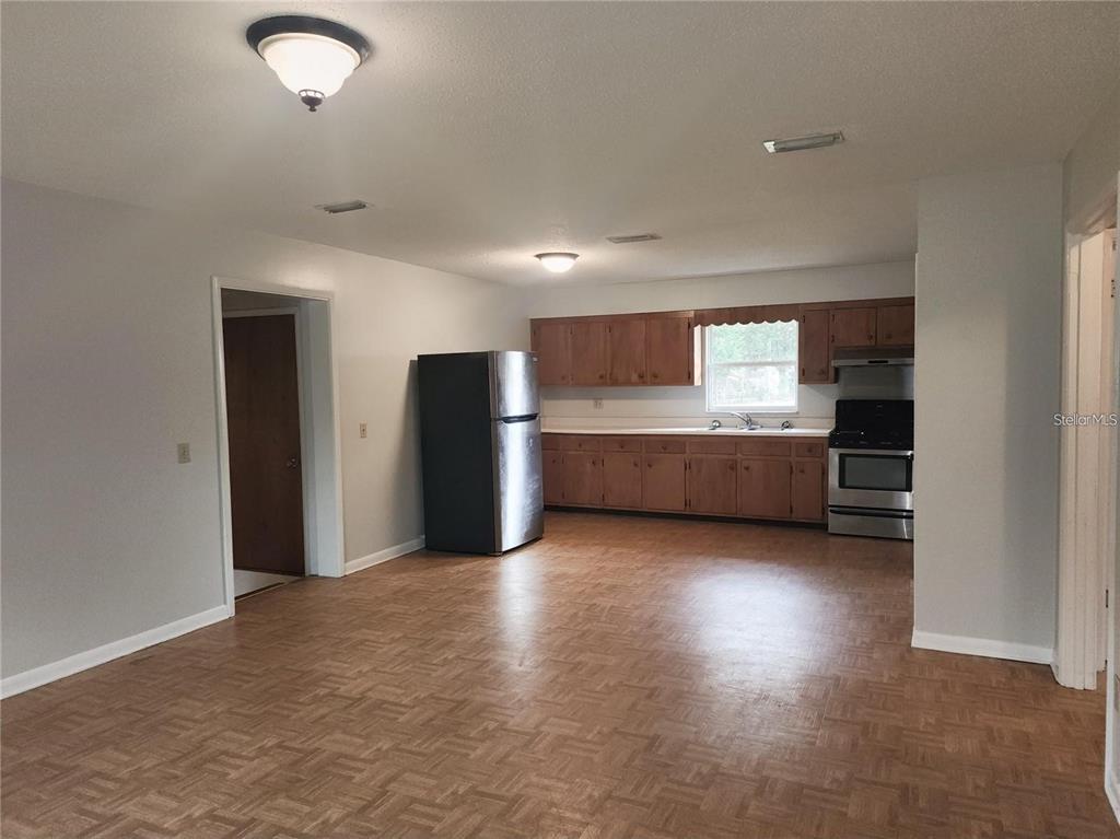 A kitchen features wood cabinets, stainless steel appliances, and a parquet floor — 420 N COURT STREET, BRONSON, FL