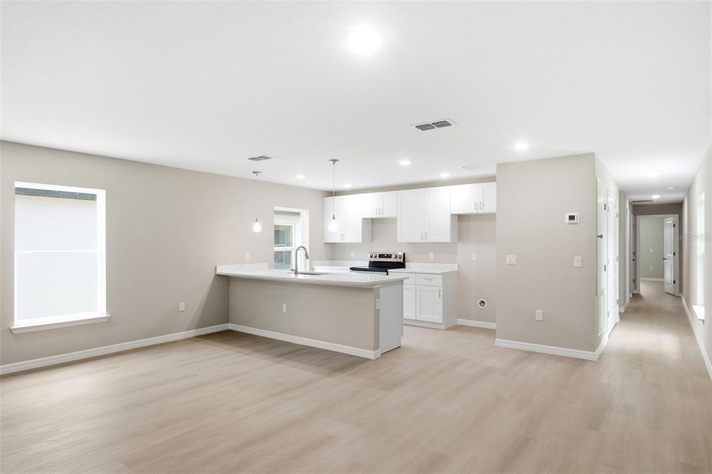 An open-concept kitchen features white cabinets, light countertops, and a breakfast bar island — 2107 SUANEE AVENUE UNIT 200, EUSTIS, FL