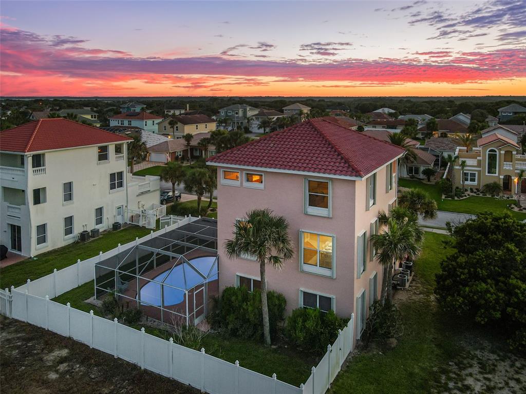 An aerial view shows a three-story pink house with a screened pool and red roof — 3817 ISLAMORADA DRIVE, ORMOND BEACH, FL