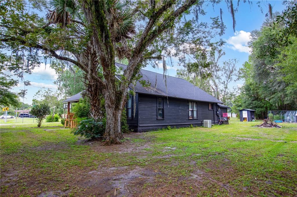 A dark-sided house sits on a grassy lot shaded by a large, moss-covered oak tree — 13328 NE 230TH COURT, RAIFORD, FL