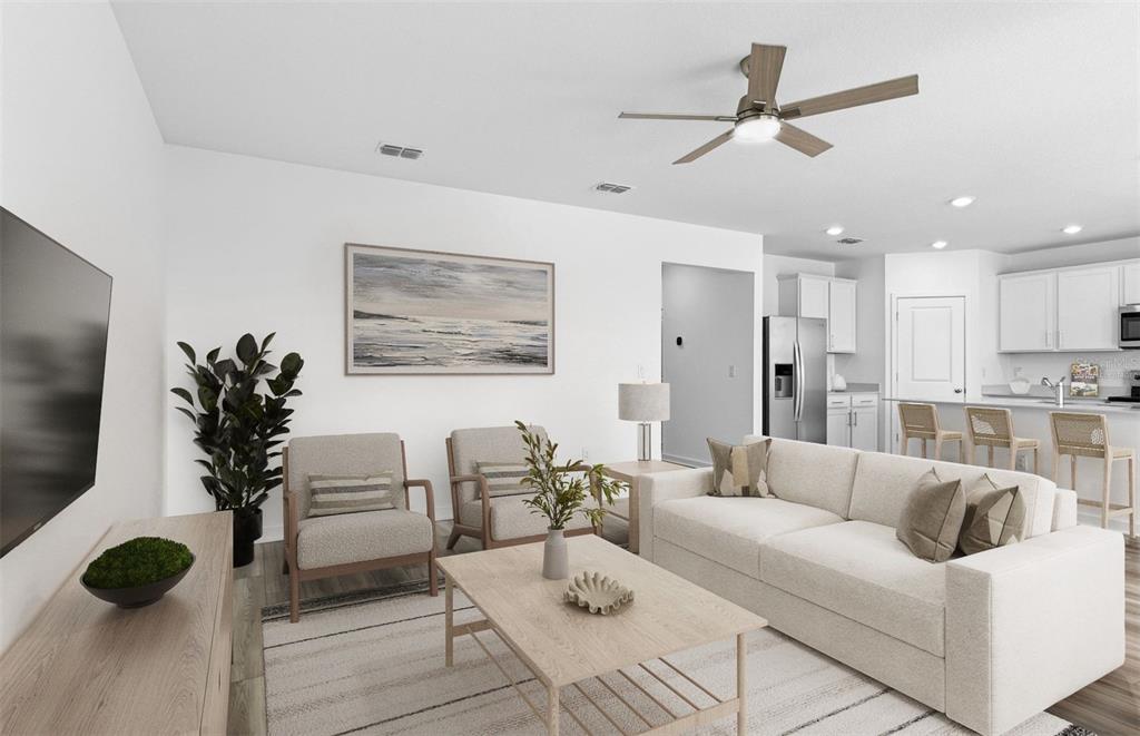 A bright living room features a sofa, two armchairs, a coffee table, and a ceiling fan — 12809 BLUE REFLECTION AVENUE, PARRISH, FL