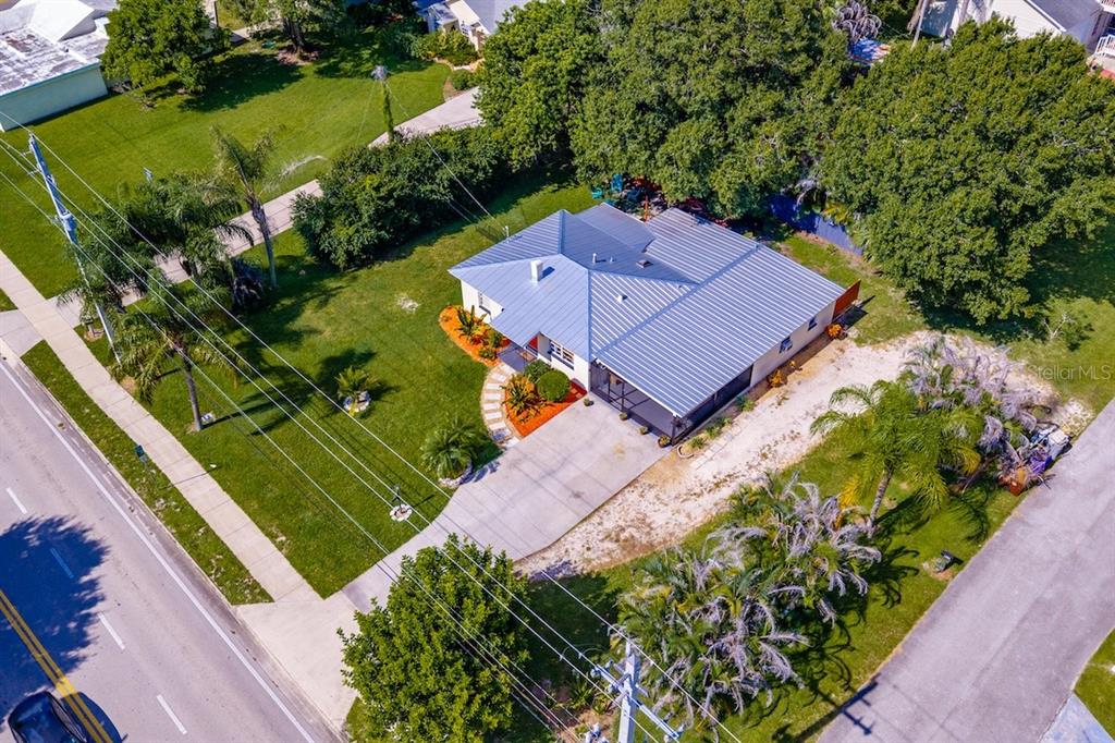 An aerial view shows a single-story house with a metal roof and a concrete driveway — 825 20TH AVENUE, VERO BEACH, FL