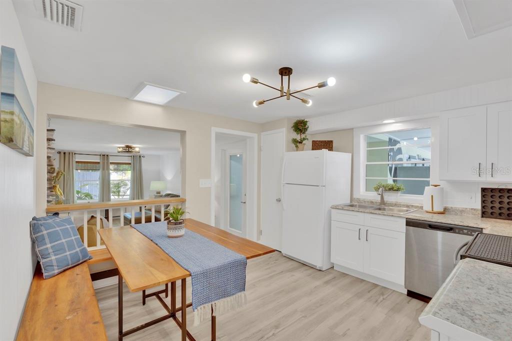 A kitchen with white cabinets, stainless steel appliances, and a wooden dining table with bench seating — 825 20TH AVENUE, VERO BEACH, FL