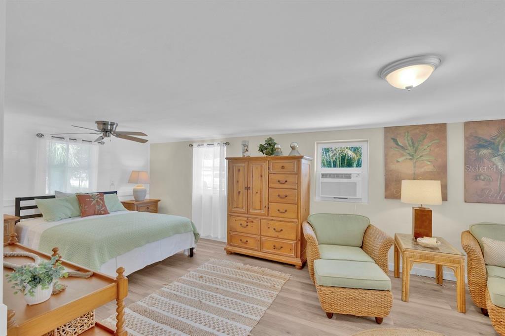 A bedroom features a bed, a wooden armoire, wicker chairs, and light-colored wood-look flooring — 825 20TH AVENUE, VERO BEACH, FL
