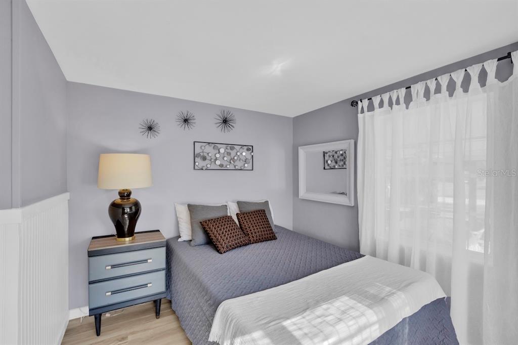 A bedroom features a bed with gray bedding, a bedside table, and wall-mounted metal decor — 825 20TH AVENUE, VERO BEACH, FL
